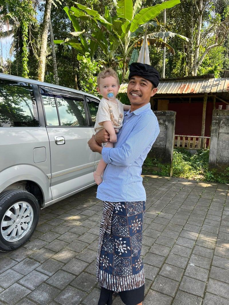 Pendi devant son véhicule, portant un enfant dans les bras